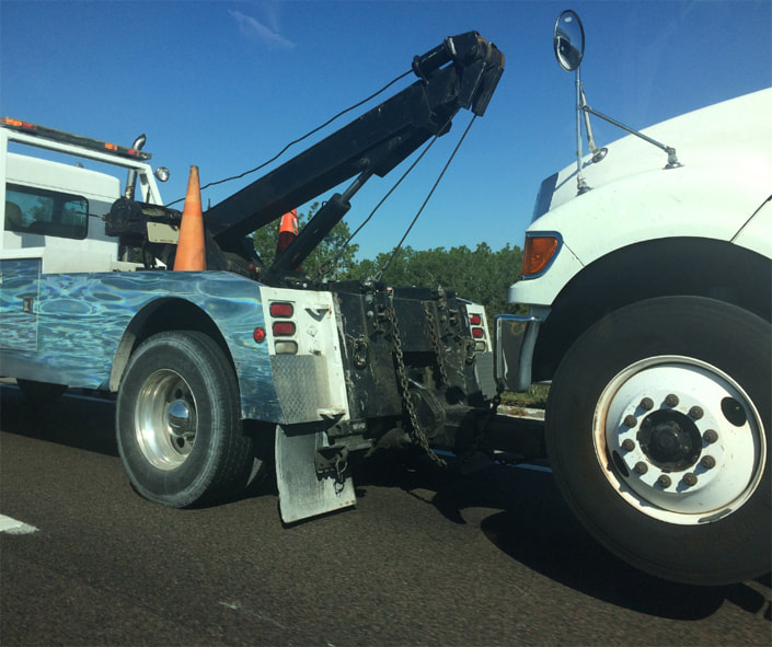 White Tow Truck towing a White Truck using a Wheel lift system